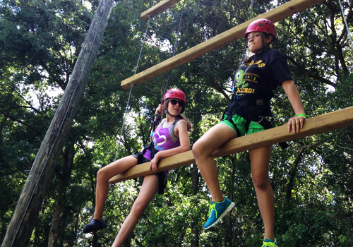 Two teenagers navigate ropes course at social skills day camp 