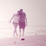 An embracing couple walk along the beach