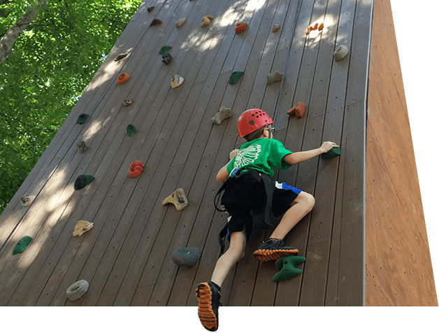 Youth scales rock wall on the ropes course at our adventure based ADHD ASD social skills camp in Orlando, Florida