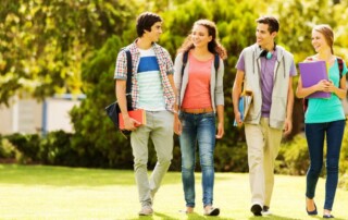Group of college students walking together on campus with backpacks and books, smiling and talking.