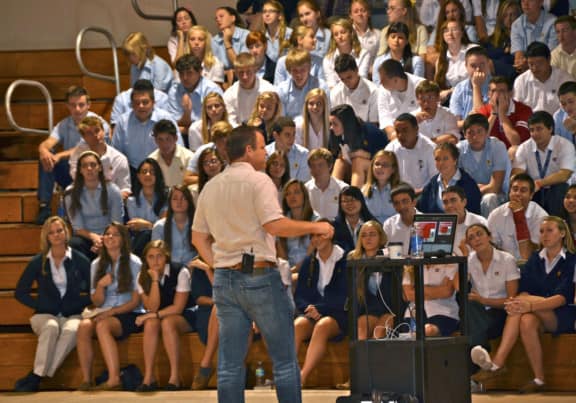 TLC counselor speaking to adolescents in school gym