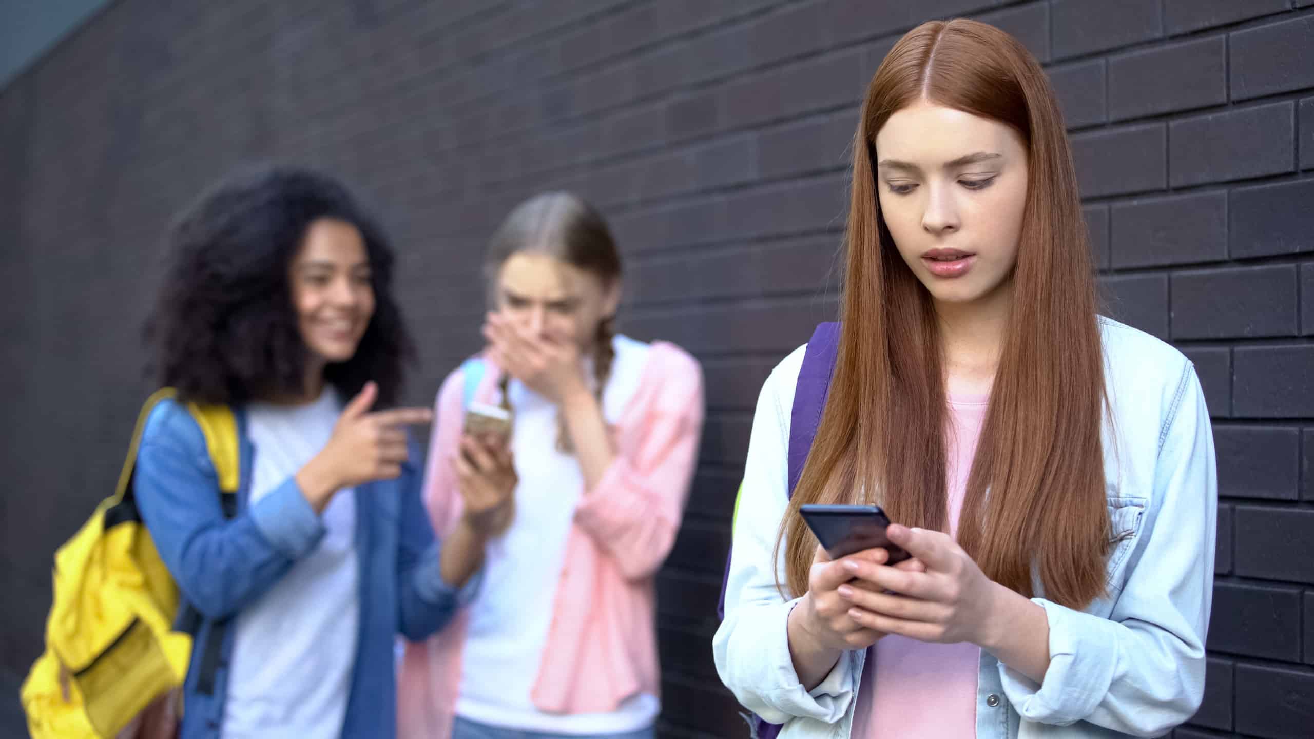 Bullied female student reading embarrassing news social networks by smartphone