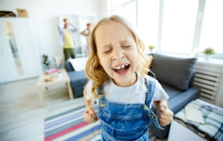 Defiant child shouting loudly while demanding something from her parents at home