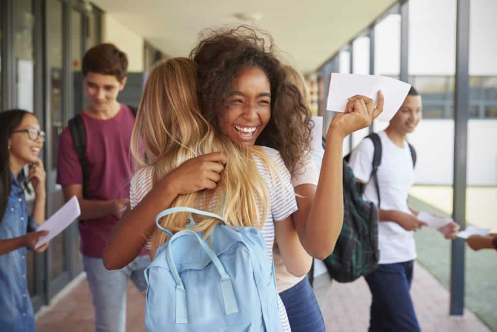 Adolescent Counseling Services Two girls celebrating exam results in school corridor