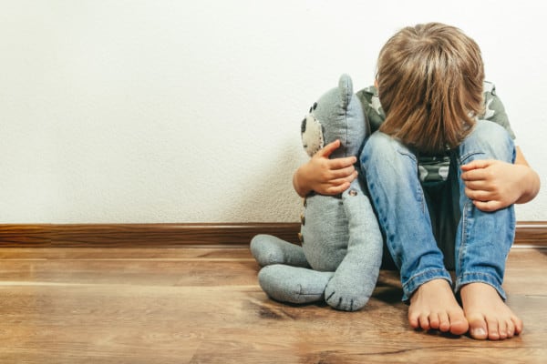 Sad, grieving child with teddy bear