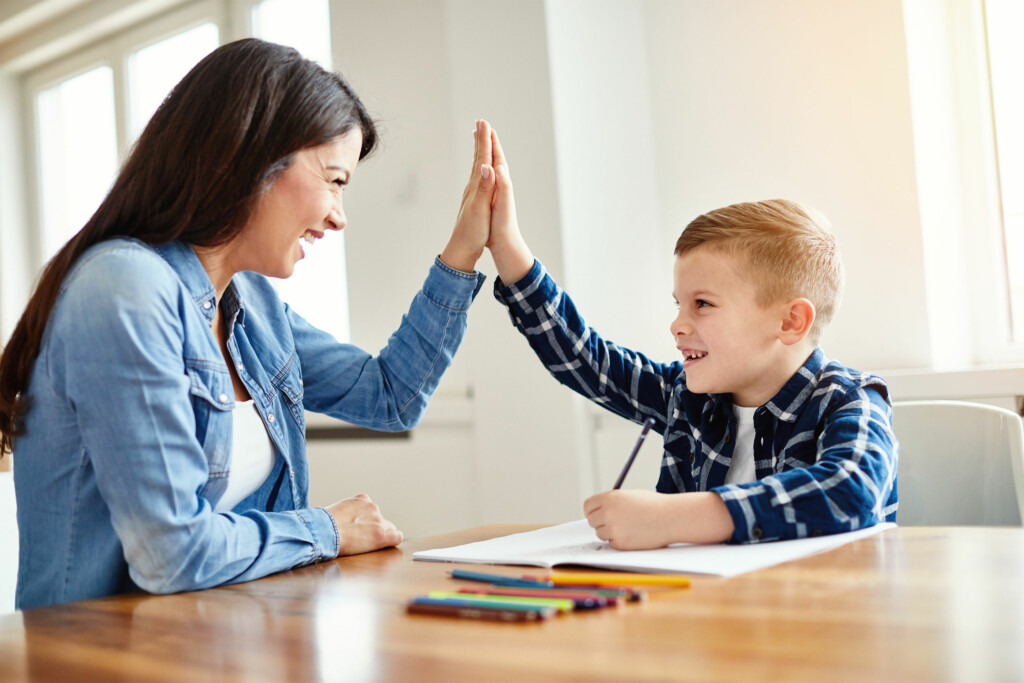 Social skills coach smiling and giving youth high five