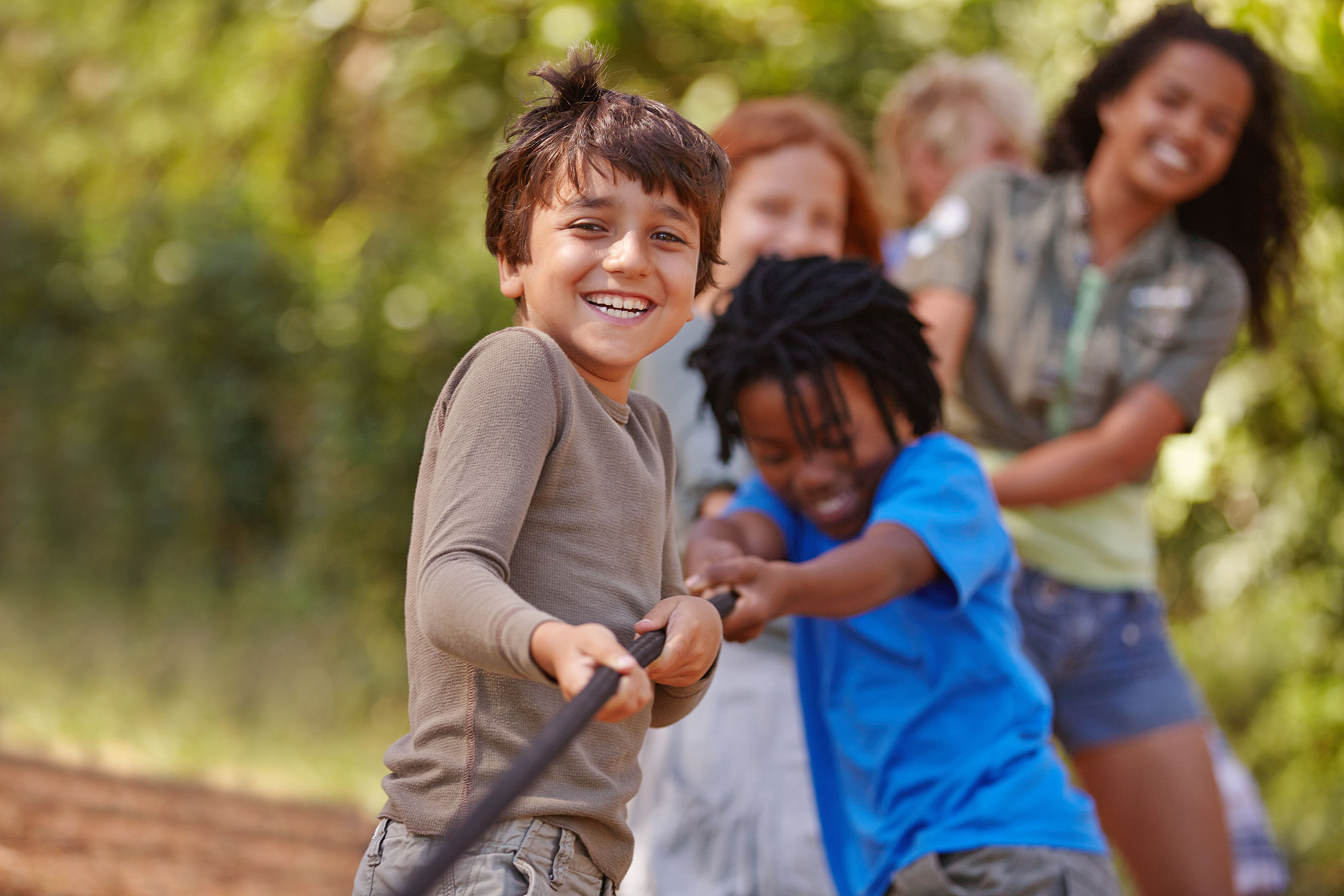 Smiling children playing tug of war in a social skills group