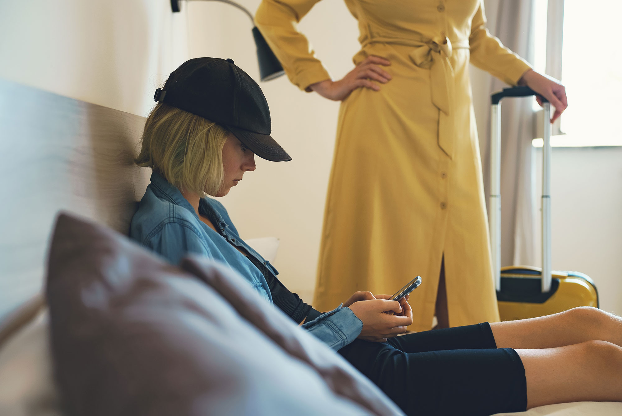 Rebellious teen wearing black had and blue jacket looks downward at her getting counseling at Total Life Counseling Center