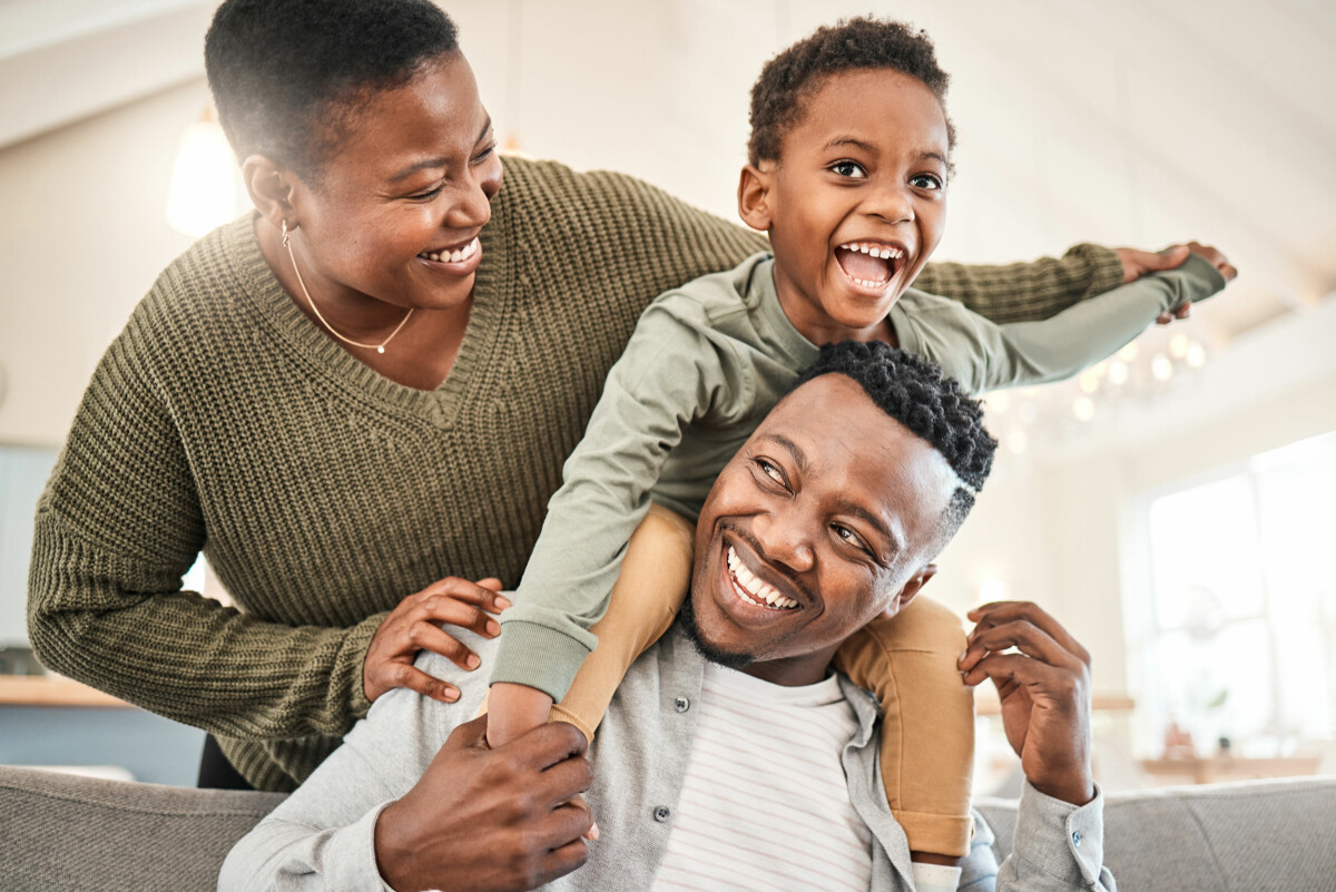 Happy young family playing together on the sofa at home.