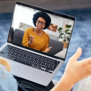 Therapist talking to home client on computer for remote therapy.