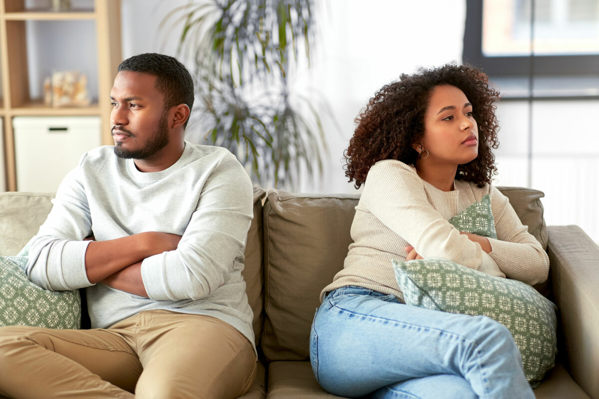 Disagreeable couple sitting on couch facing away from one another