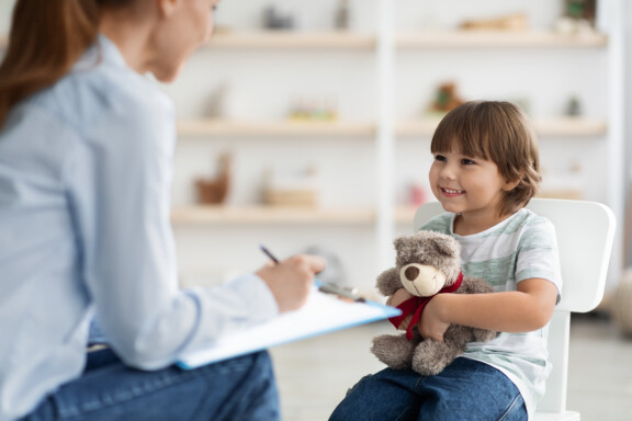 Female Play therapist helping a boy holding a teddy bear with mental health issues at Total Life Counseling Center Dallas Texas.