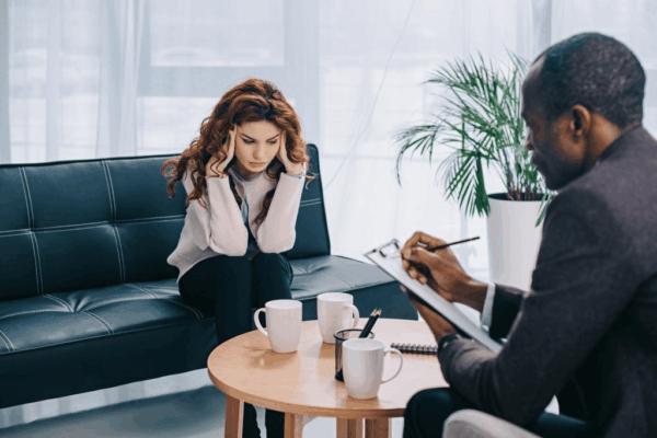 Upset young woman talking to psychotherapist