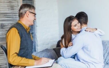 Couple embracing during a marriage counseling session while speaking with a therapist about improving their relationship and communication_ - Total Life Counseling for Children, Teens, Adolescents and Adults in Orlando Winter Park Clermont Lake Mary and Central Florida Marriage Counseling Session Helping Couples Strengthen Their Relationship