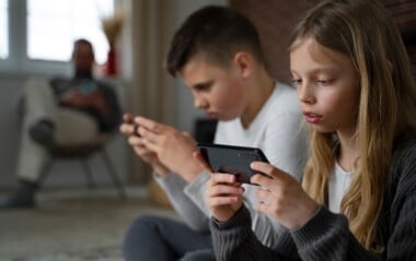 image - 2026-07-17T150216512 - Total Life Counseling for Children, Teens, Adolescents and Adults in Orlando Winter Park Clermont Lake Mary and Central Florida Two children sit closely indoors, each focused on a handheld gaming console.