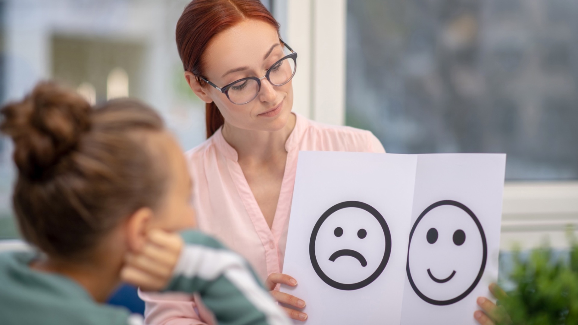 Psychologist showing a child happy and sad face drawings during assessment Psychologist showing a child happy and sad face drawings during assessment