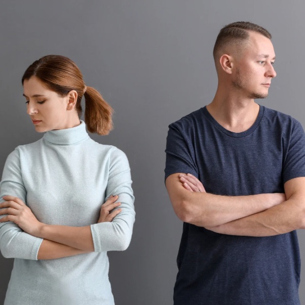 Couple standing back-to-back with arms crossed, showing conflict Couple standing back-to-back with arms crossed, showing conflict