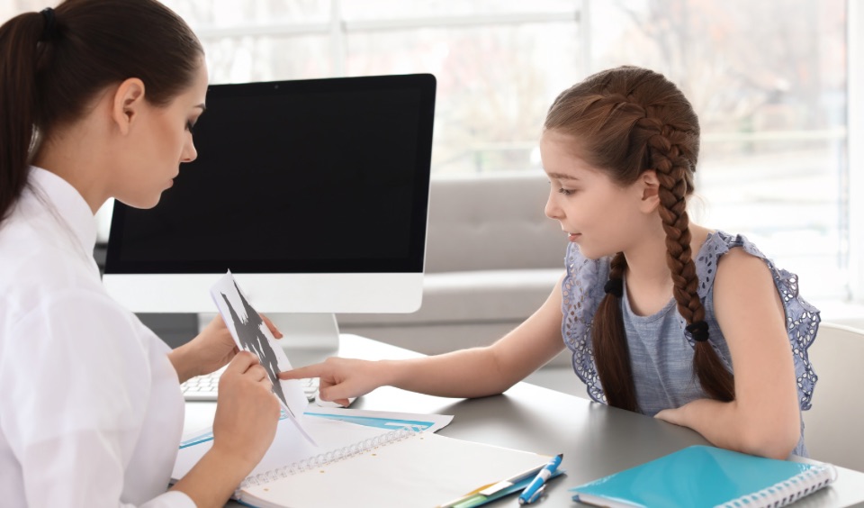 Child undergoing psychological assessment with a clinician in an office setting. Child undergoing psychological assessment with a clinician in an office setting.
