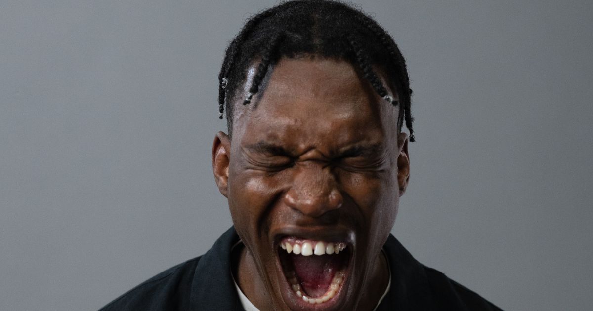 Closeup of a man screaming in anger Anxious mother consumed by worry holds baby while staring blindly into the distance. Supportive husband looks upon his wife with concern.