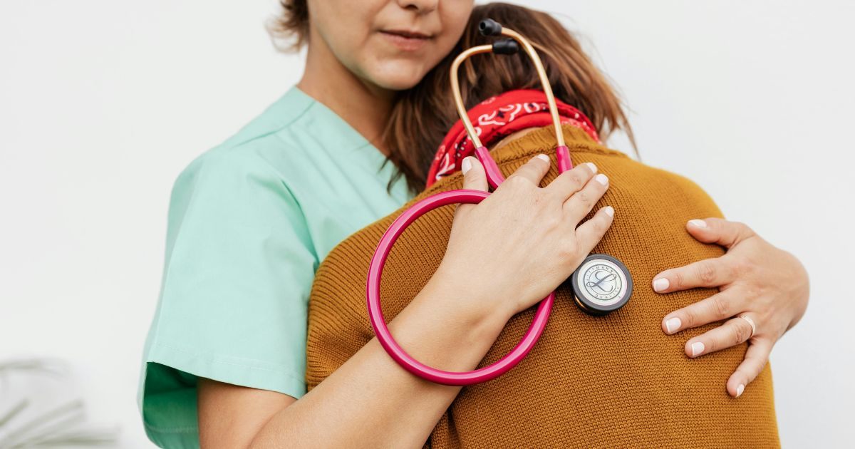 A medical practitioner hugging her patient A medical practitioner hugging her patient