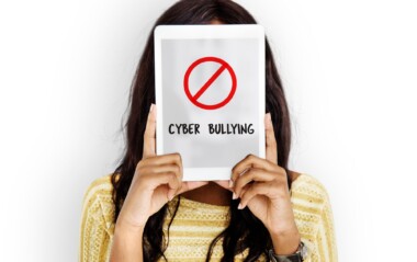 Person holding tablet with “Cyber Bullying” and stop icon